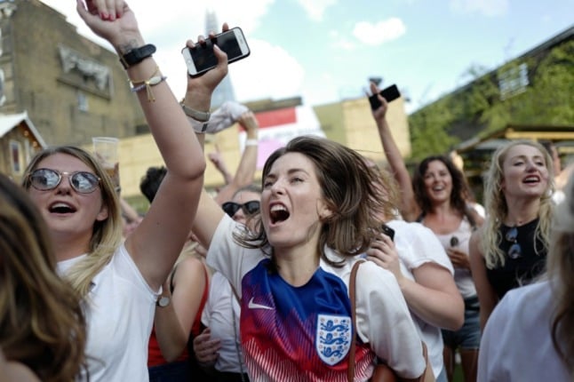 England fans celebrate while watching the football (Photo by Tolga AKMEN / AFP)