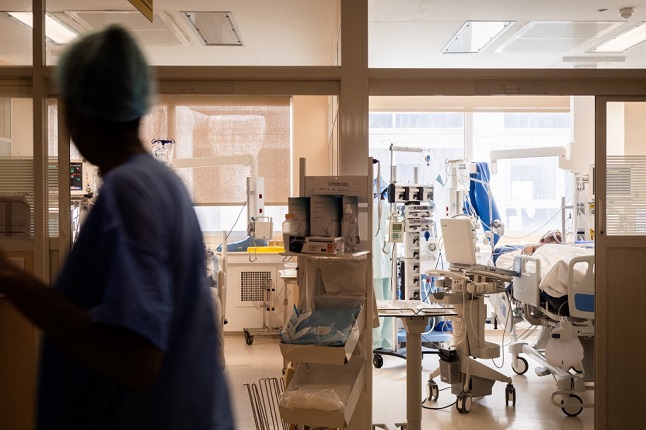 Nurse walks past intensive care bed